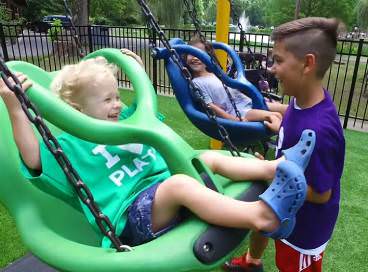Child pushing other children in child safe chair swings
